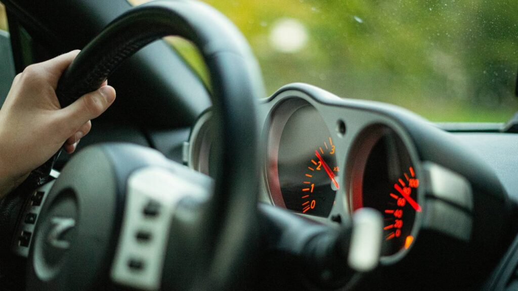 A closeup photo of a person holding a steering wheel and driving the car
