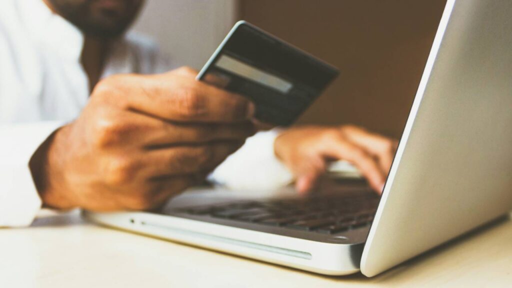 A closeup photo of a man using his credit card to buy stuff online