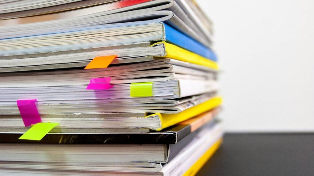 A dozen of colourful documents stacked one upon another