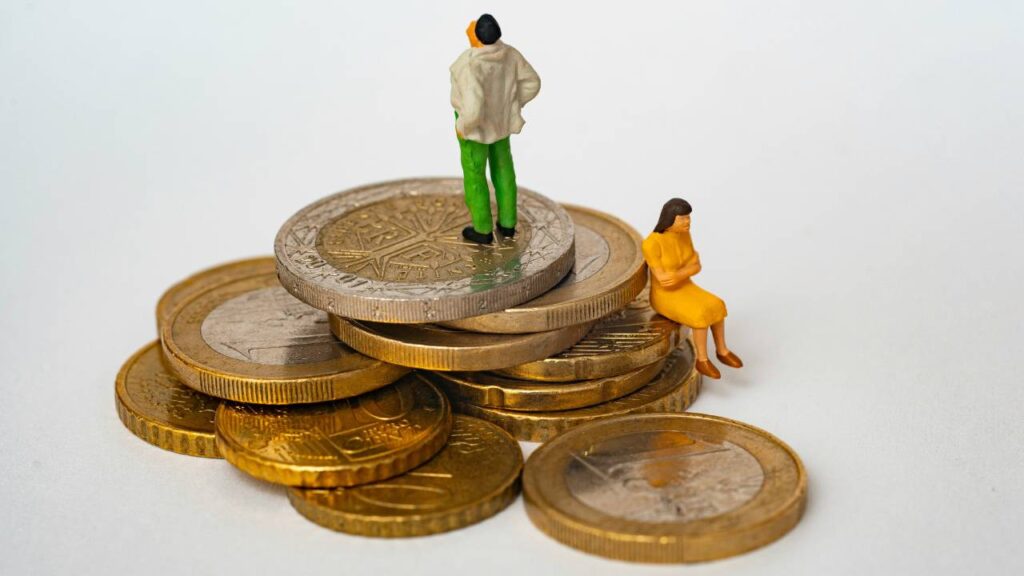 Figurines of a man and a woman placed onto a stack of Euro coins