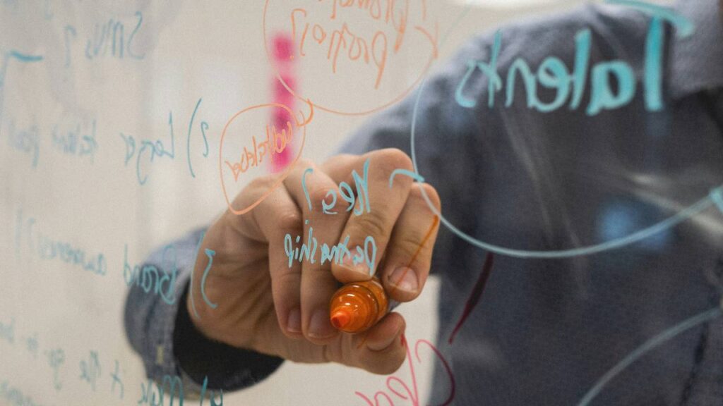 A closeup photo of a man taking notes on a transparent board