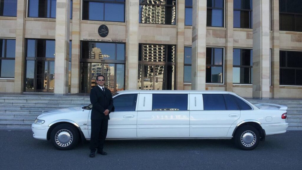 A chauffeur standing in front of a white limousine