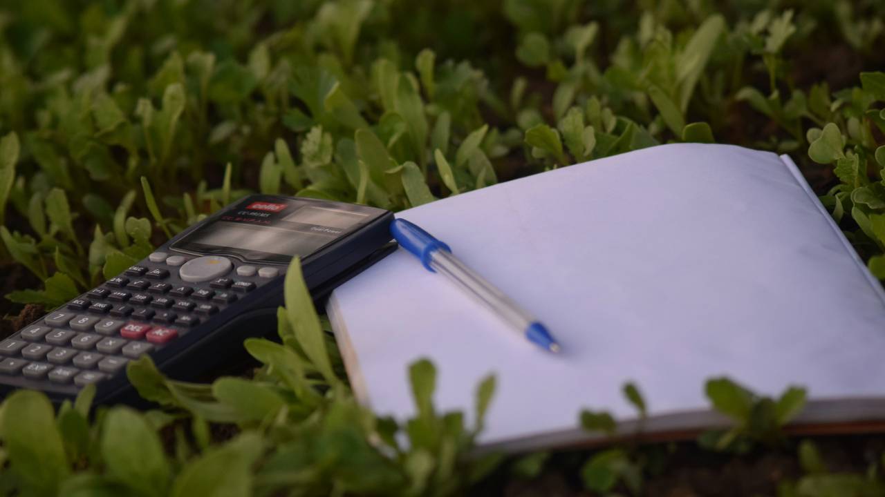 A calculator and a notebook laying on green grass