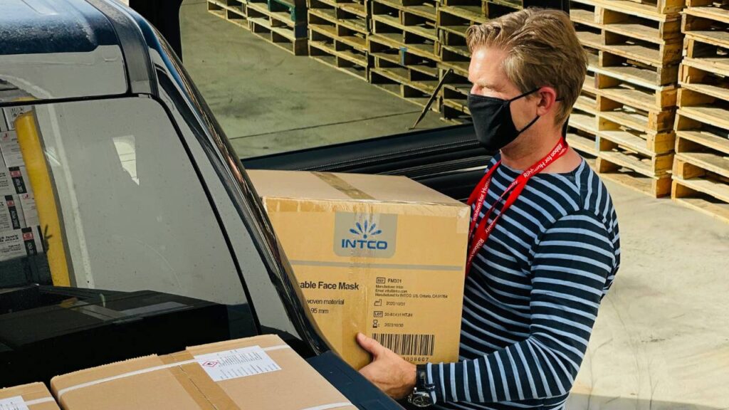 A man holding a cardboard box in front of a vehicle