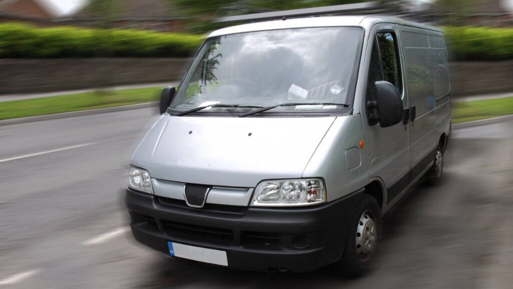 A photo of a silver van going down the road