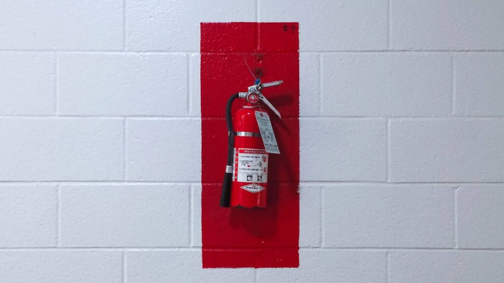 A white wall with a red fire extinguisher on it