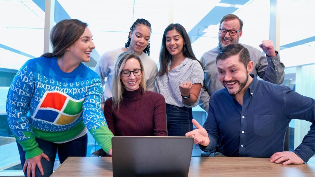 Several happy office workers looking at the laptop and laughing together 