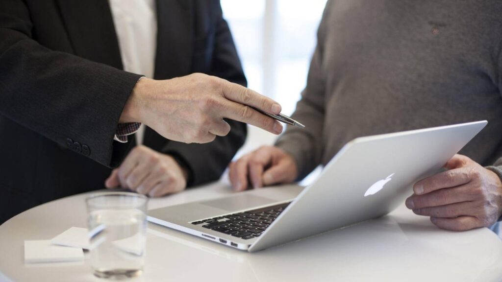 A management consultant showing something on a laptop screen with his pen 