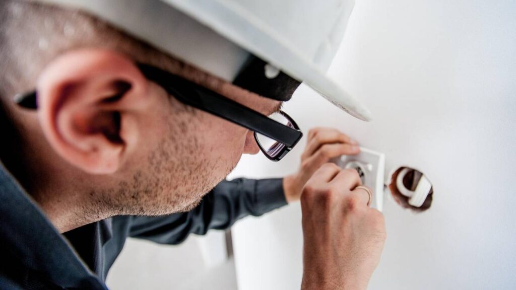 An electrician inspecting a wall outlet 