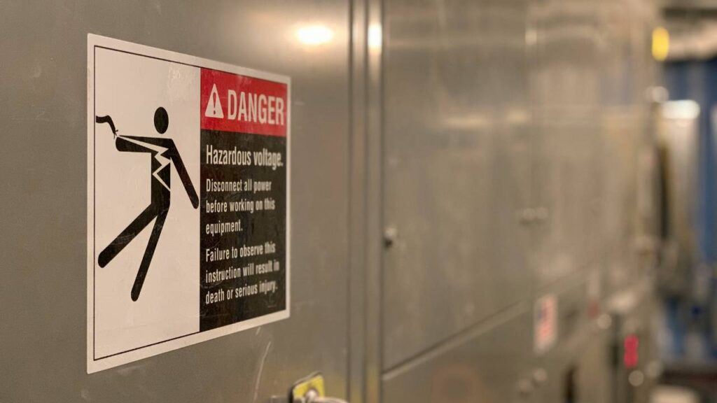 A sign on an electrical box saying "danger - hazardous voltage"